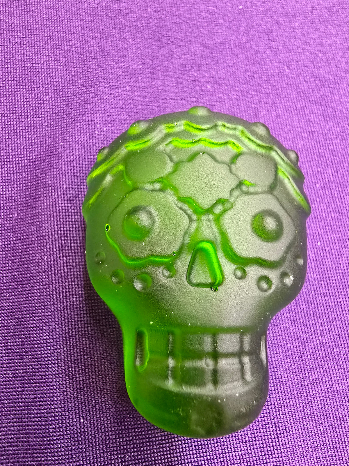 A translucent green skull with Dia De Los Muertos type designs.